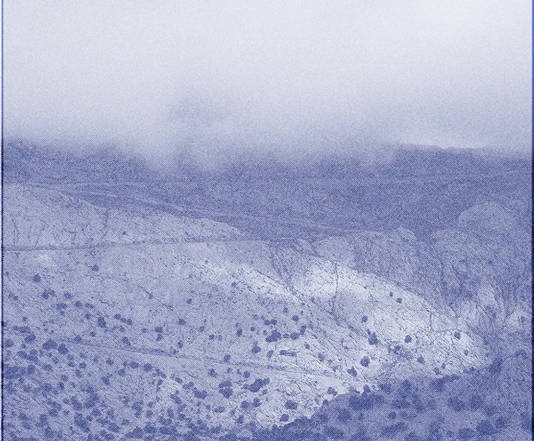 Mountain in the Serra de Tramuntana in Mallorca covered by sparse vegetation at the bottom and by clouds at the top.